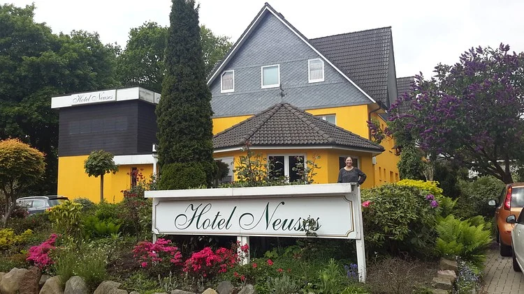 Hotel Neuses mit gelber Fassade und Blumengarten
