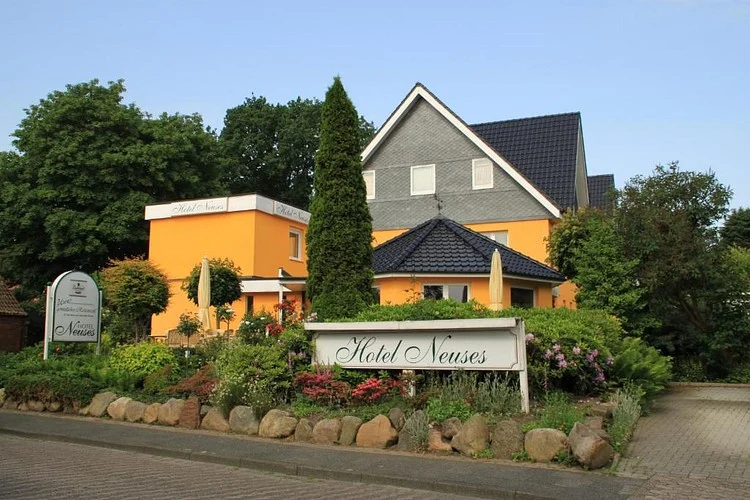 Hotel Neuses in Cuxhaven-Altenwalde: gelbes Haus mit Schild und Garten