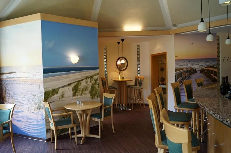 Sitzecke im Restaurant vor einem Strand-Wandbild