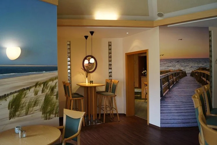 Sitzecke vor Strand-Wandbildern im Restaurant