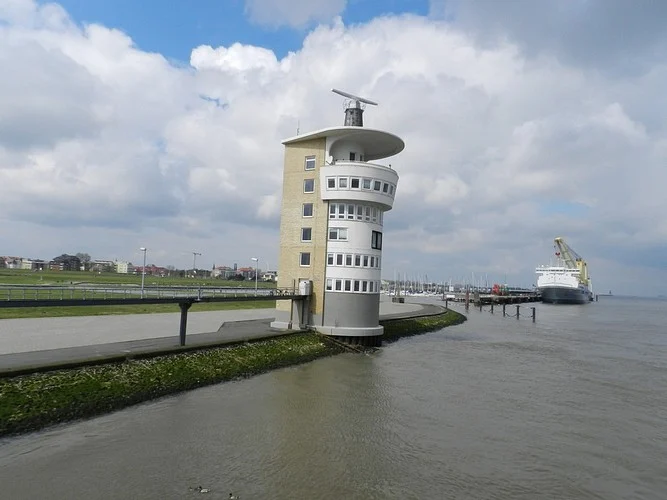 Weißer Turm am Wasser mit Wolkenhimmel