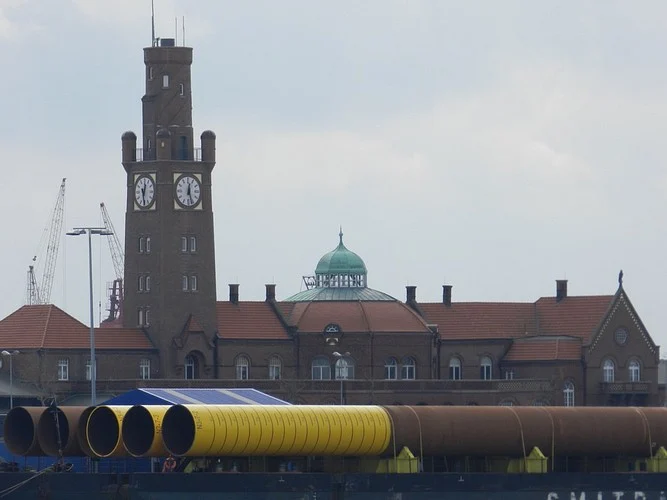 Backsteinturm mit Uhr hinter Rohren