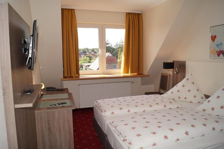 Zimmer unter dem Dach mit Doppelbett, Fenster und Vorhängen